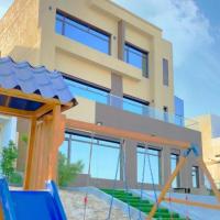 a house with a playground in front of it at منتجع اووه يامال البحري في الخيران OOh Yaa Mal, Al Khīrān