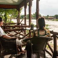 a man and a woman sitting at a table near a river at Nongsak Riverside Guesthouse & Nongsak Guesthouse, Don Khone