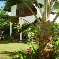 a palm tree in front of a house at Fairy-Tern Chalets Cerf Island
