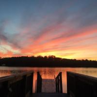 a sunset over a body of water with a dock at Bespoke Lake Cottage, New Minas