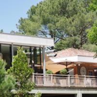 a house with a balcony with an umbrella at Domaine du Ferret Restaurant & Spa, Cap-Ferret
