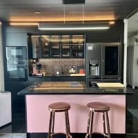 a kitchen with two bar stools and a pink counter at Upea huoneisto Raision keskustassa