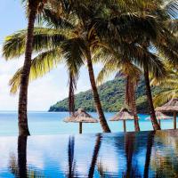 a swimming pool with palm trees and the ocean at Beach Club, Hamilton Island