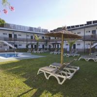a yard with lounge chairs and an umbrella and a pool at Campomar Playa, El Puerto de Santa María