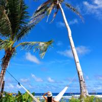a man laying in a hammock under two palm trees at Bamboo Surf Beach, San Isidro