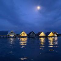 a row of houses on a dock in the water at night at ADIL WATERHOUSE RESORT, Semporna
