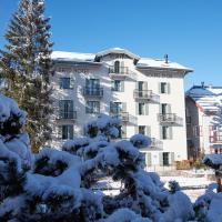 a building covered in snow in front of a tree at Grand Hotel Soleil d'Or, Megève