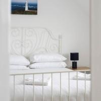 a white bed with a white headboard and a lighthouse at Modern newly refurbished house 10 minute walk from Lahinch