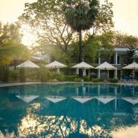 a swimming pool with a palm tree and umbrellas at Anantamaa Hotel, Trincomalee