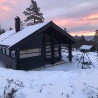 a cabin with a snow covered roof in a field at Myrullen - Cabin at Sørbølfjellet, Flå