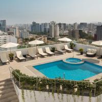 a pool on the roof of a building with chairs and umbrellas at Costa del Sol Wyndham Lima City