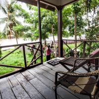 a rocking chair on a porch with a view of the street at Lao Long Riverside and Budget Garden Guesthouse, Don Khone