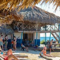 a group of people on the beach near a straw hut at Dahlandia, Isla Mucura