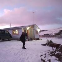 a person standing in the snow in front of a house at Cabañas La Frontera., Puerto Natales