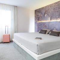 a bedroom with a large white bed and a pink suitcase at Hotel Macià Granada Five Senses Rooms & Suites
