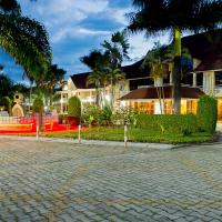 a house with palm trees in front of a brick driveway at Hotel Safari Gate, Bujumbura