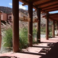 a covered walkway with a building and some grass at Mirador Del Virrey, Cabañas Boutique, Purmamarca