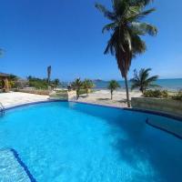 a large swimming pool with a palm tree and the ocean at Beach View Palace, Porlamar