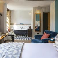 a bedroom with a bed and a bathroom with a tub at The Old Stocks Inn, Stow on the Wold