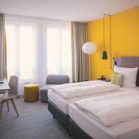 a hotel room with two beds and a desk at Vienna House Easy by Wyndham Leipzig