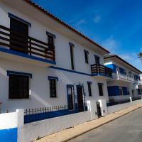 a white building with blue accents on a street at Apartamento Rosa, Porto Covo