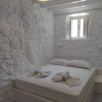 a white bedroom with a bed with a window at Oniropagida Nisyros apartment #1, Nikiá
