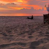 a person sitting on the beach at sunset at Sun Smile Beach Koh Jum, Ko Jum