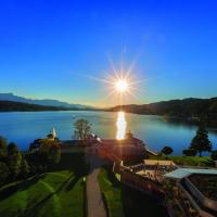 a view of a lake with the sun shining on the water at Werzers Hotel Resort Pörtschach, Pörtschach am Wörthersee