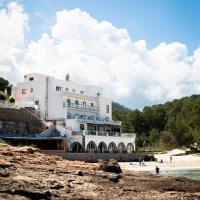 a white building on the beach with people on the beach at Hostal La Cigüeña, Portinatx
