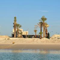 a beach with palm trees and the water at @Q8SDAIR_RV, Al Khīrān