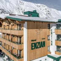 a building with snow covered mountains in the background at Hotel Enzian & Apartmenthotel Johannes, Obergurgl