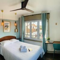a bedroom with a bed with a ceiling fan and a window at Hotel Bistrot FINE, Anglet
