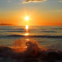a wave in the ocean with the sun in the sky at Logas Beach Studios Peroulades Corfu