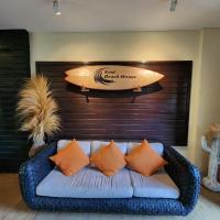 a couch with pillows and a surfboard on a wall at Kent Beach House, Canggu