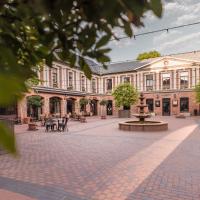 a building with a courtyard with tables and trees at Art Hotel Roma, Liepāja