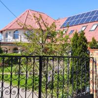 a house with a fence and a solar roof at Village Garden Family Guest House, Tiszakanyár