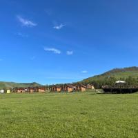 a large green field with houses in the background at Bayan Mongolian Resort, Narst
