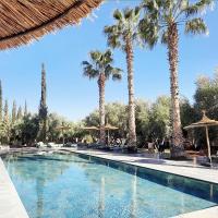a swimming pool with palm trees and umbrellas at Domaine de Tameslohte, Tameslouht