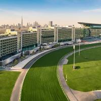 a large building with a green lawn in front of a city at The Meydan Hotel Dubai