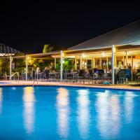 a swimming pool in front of a restaurant at night at Exmouth Escape Resort