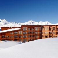 a building in the snow with mountains in the background at Résidence Prestige Odalys Edenarc, Arc 1800