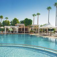 a large swimming pool with chairs and palm trees at Ajax Hotel, Limassol