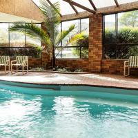 a swimming pool with two chairs and a group of windows at Pinnacle Holiday Lodge, Halls Gap