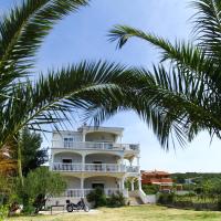 a large white house with palm trees in front of it at Apartments Natali, Sveti Petar