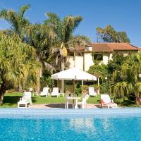 a pool with chairs and a table and a house at Hotel Riviera, Villa Gesell