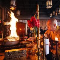 a monk sitting at a table in a room with a fire at Kumagaiji, Koyasan