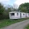 caravan nestled away amongst trees on edge of farm yard