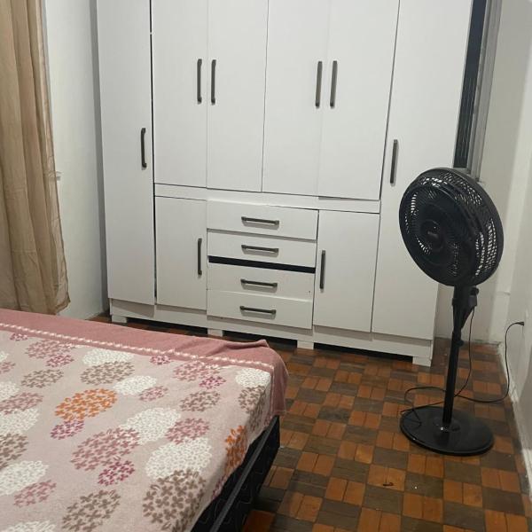 Quarto com sacada possui cama de casal, ventilador e guarda-roupa