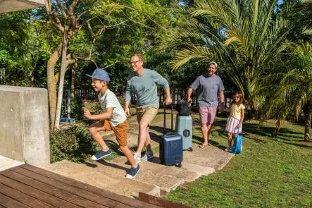2 men and their 2 kids smiling and laughing as they enter a property.